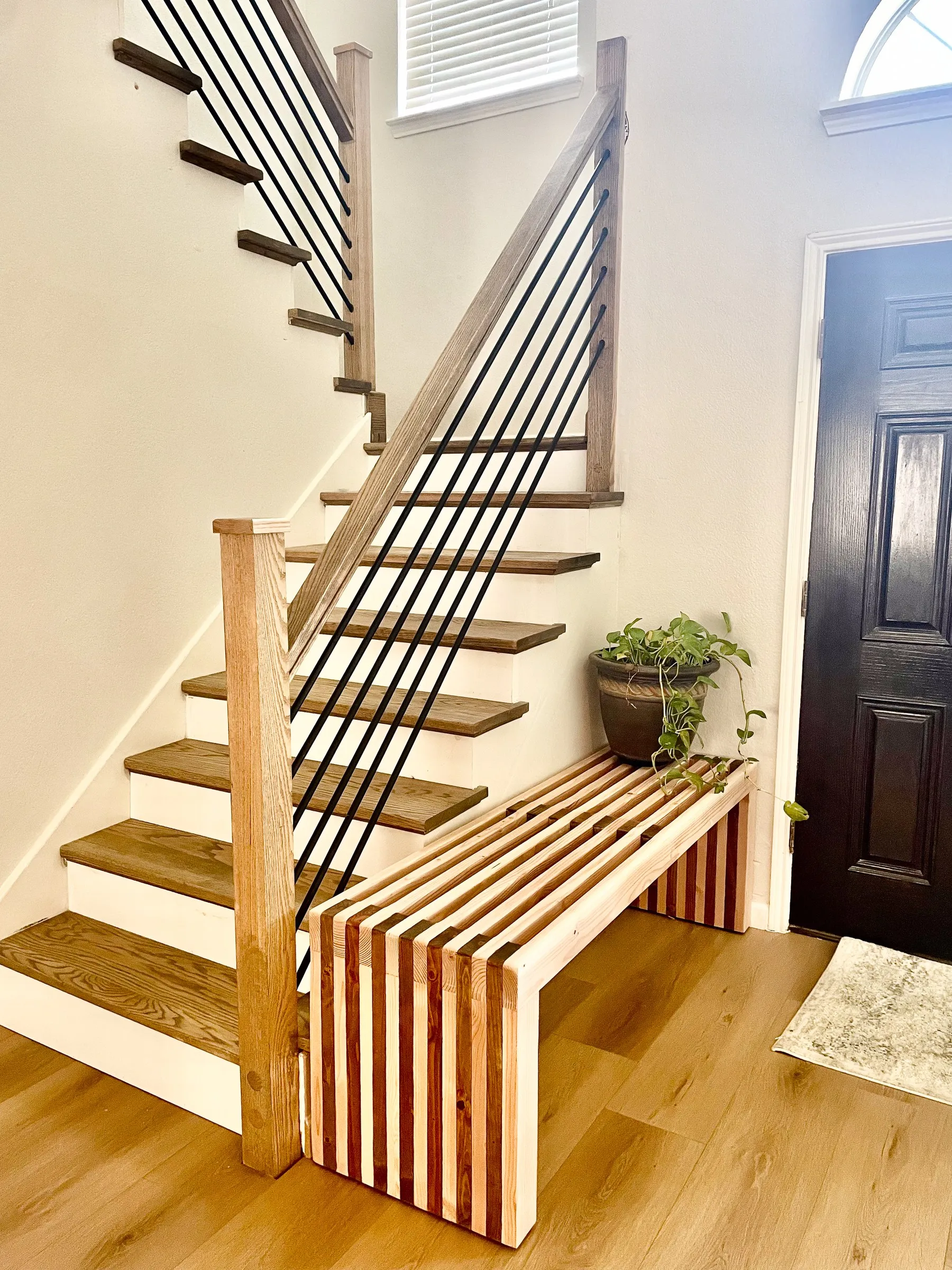 Custom two-tone slatted wood entryway bench beside staircase by IonBuilds Murphy TX