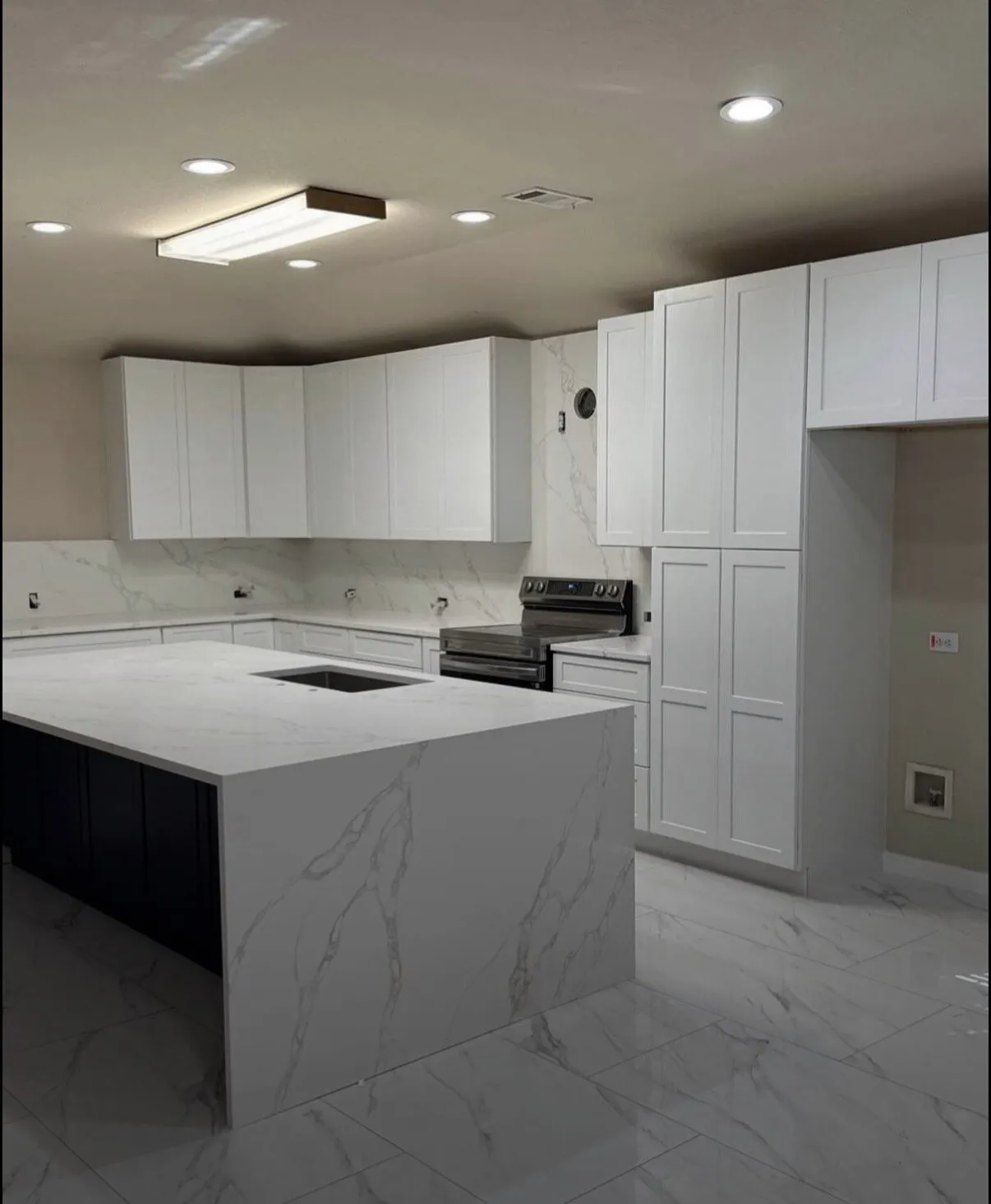 White kitchen with black island and waterfall countertop by IonBuilds