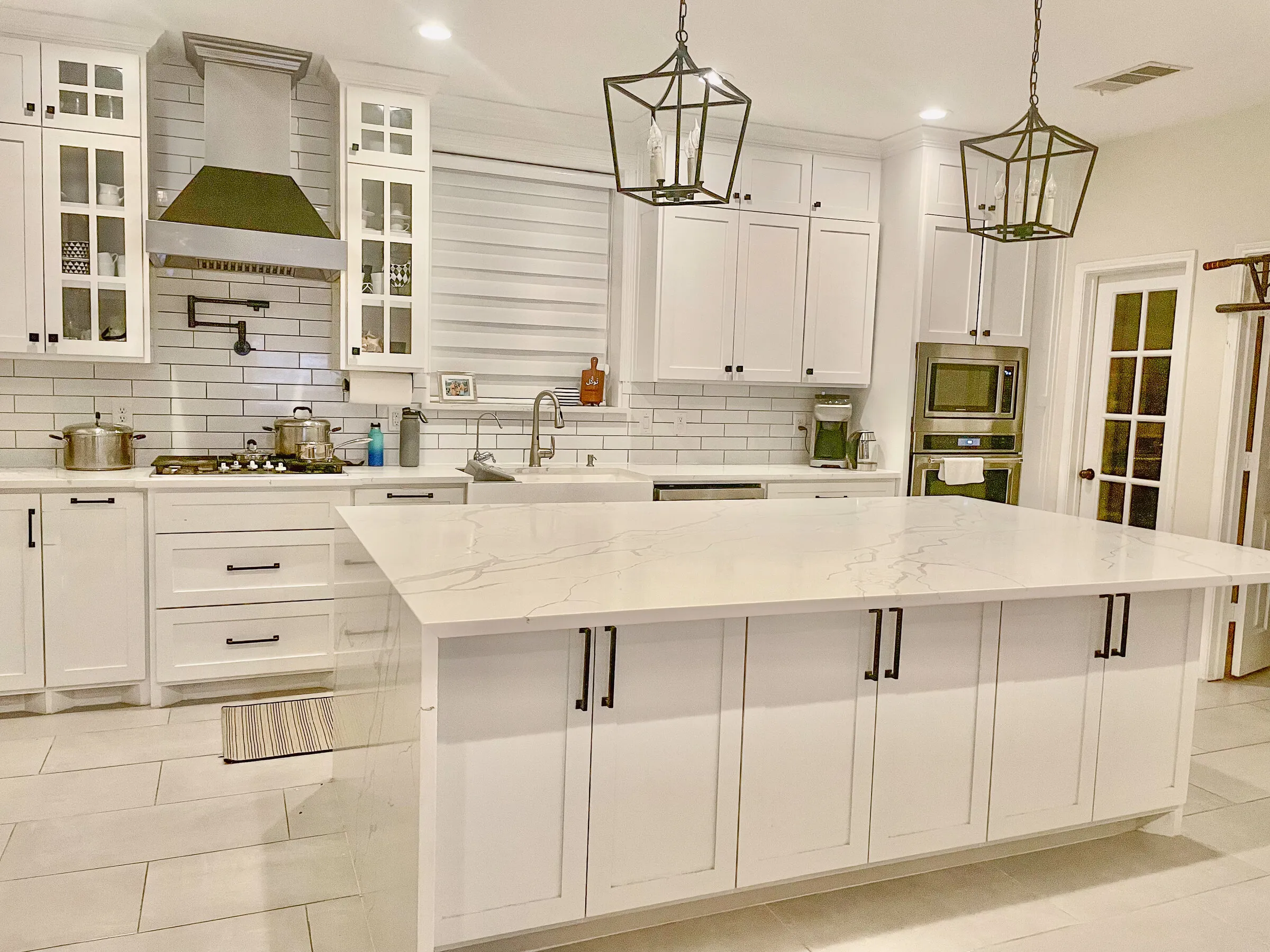 Finished white kitchen with green range hood and large island by IonBuilds