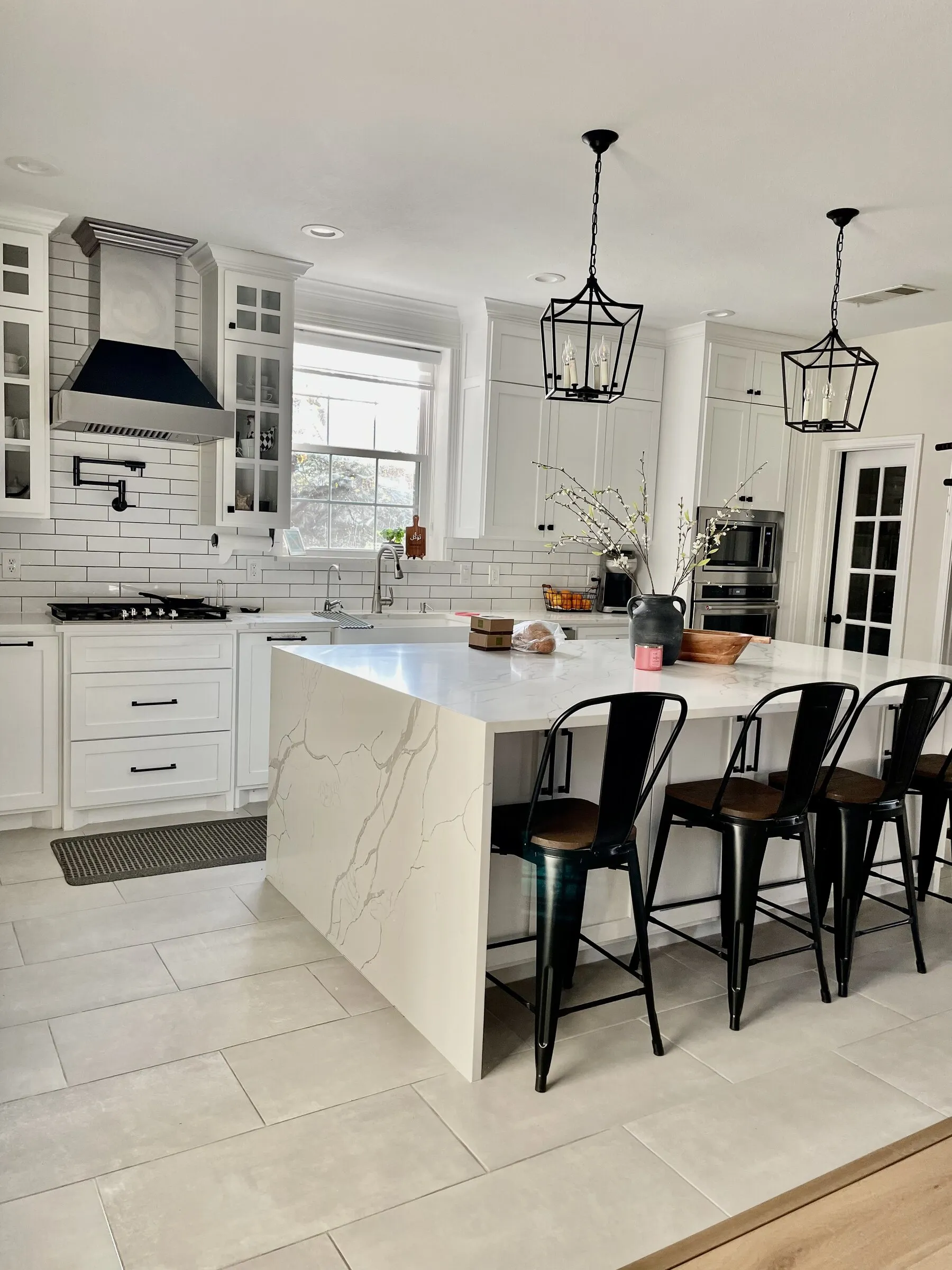 Finished white kitchen with waterfall island and custom range hood by IonBuilds