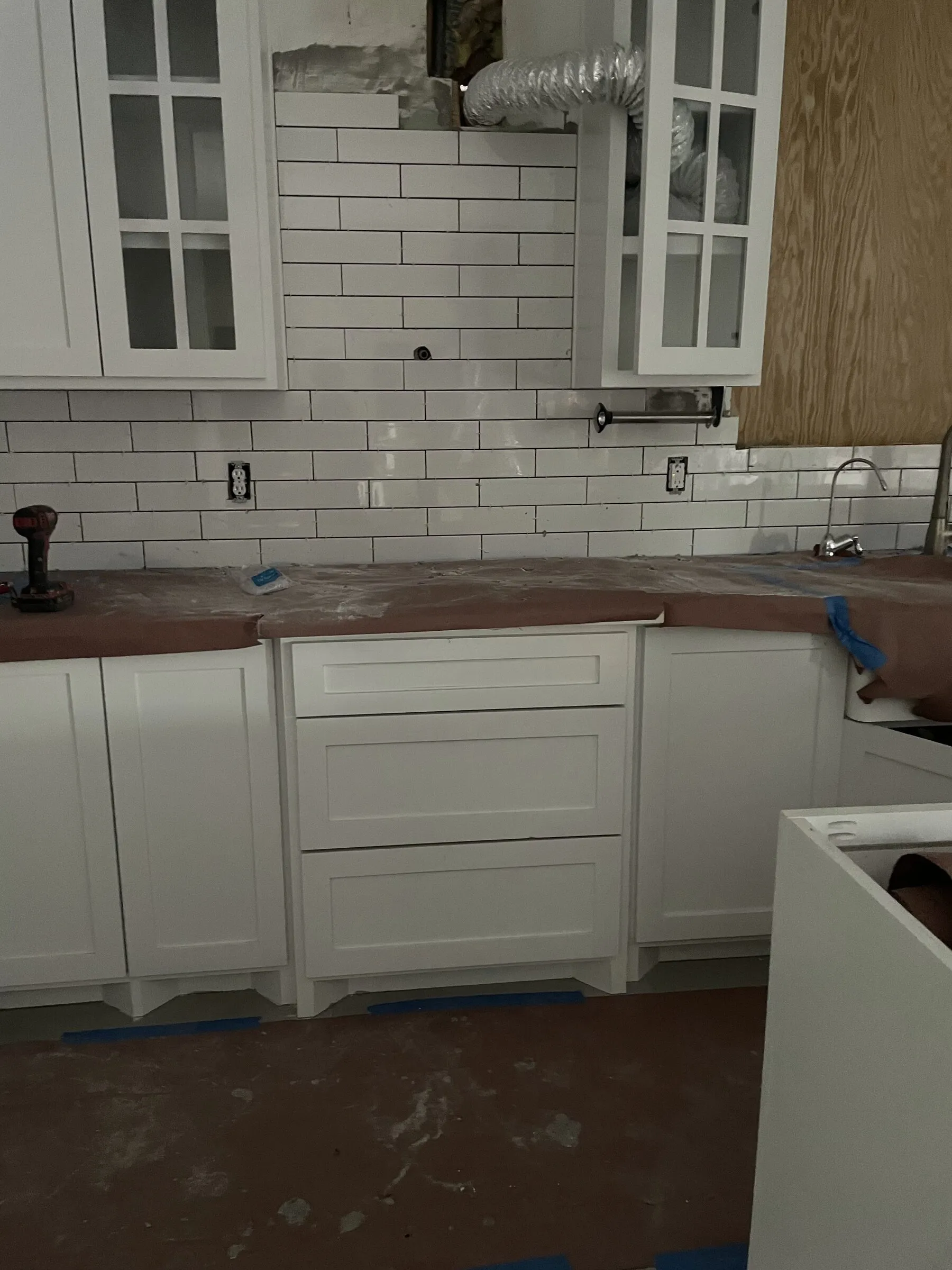 Close-up of white shaker cabinet drawers and glass doors by IonBuilds